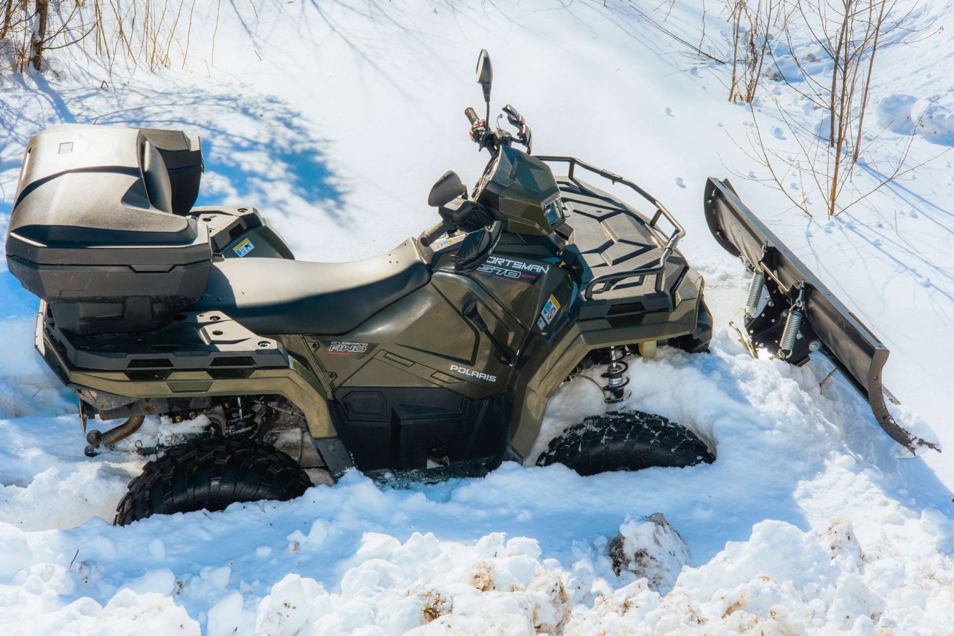 Polaris Sportsman -mönkijä lumihangessa aura edessä
